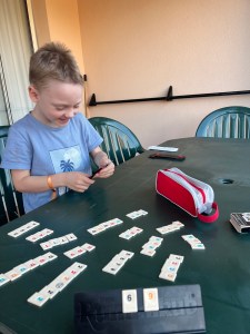 A six year old child grinning as he wins a game of Rummikub